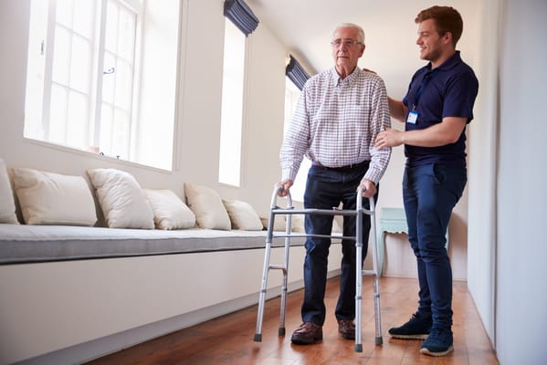 A caregiver assisting an elderly resident in a hallway