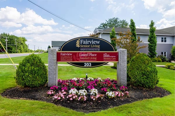Sign for Fairview Senior Living with flowers and grass.