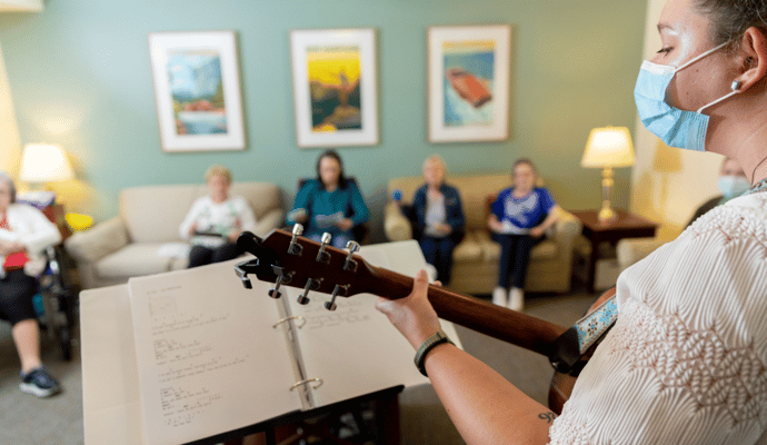 Staff member playing guitar for residents in a common area