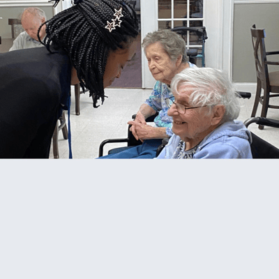 Care staff interacting with smiling residents in a cozy room
