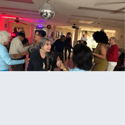 Residents and staff dancing in a vibrant activity room