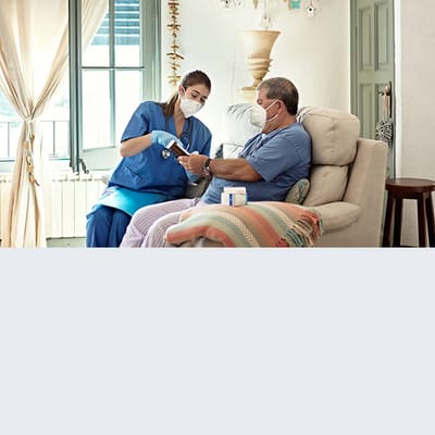 Healthcare staff assisting a resident in a cozy interior