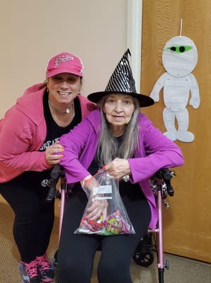 Resident receiving a Halloween treat bag with staff member