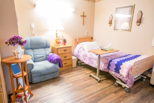 A cozy resident room with bed and chair