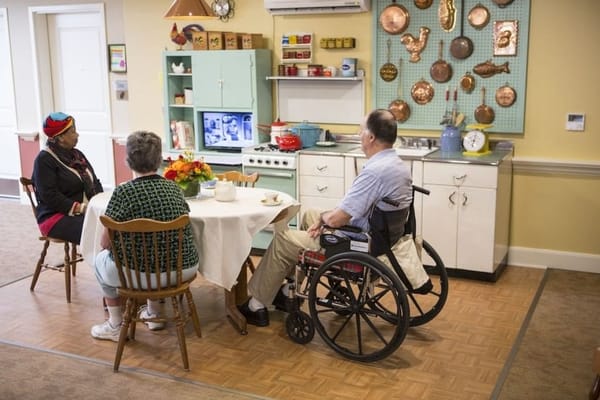 Residents enjoying conversation around a table in a communal kitchen