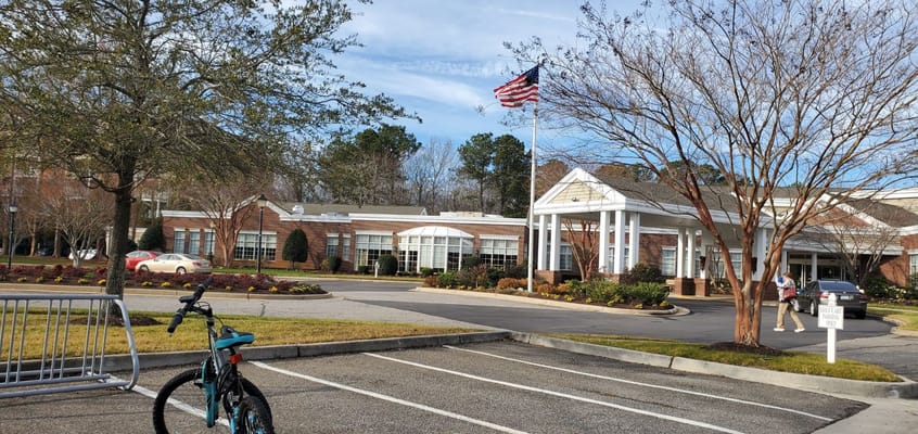 Facility exterior with flag and landscaped front entrance