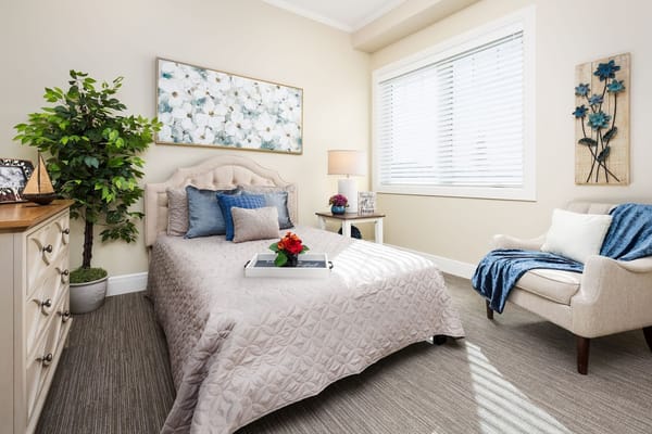 Bright and welcoming bedroom featuring a bed, chair, and decorative elements.