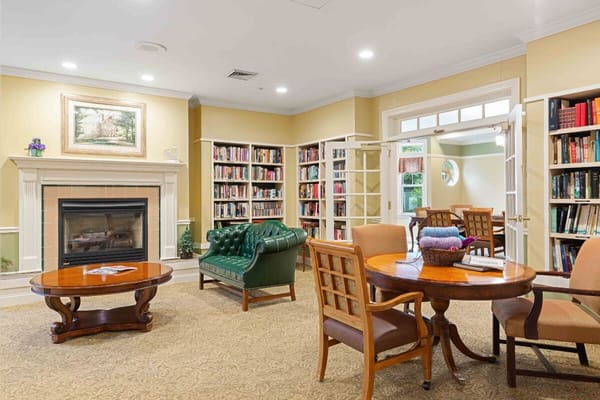 Lounge with green leather chair, wooden table, and bookshelves.