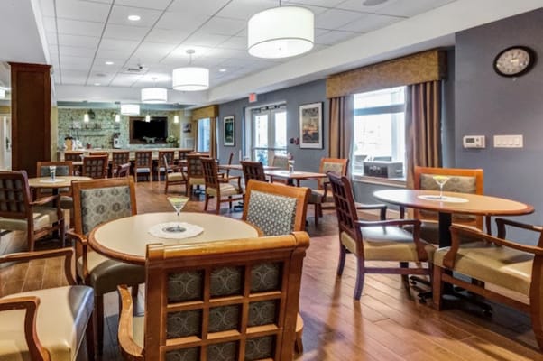 Spacious dining area with tables and chairs in a senior living facility.
