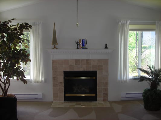 Well-lit living room featuring a fireplace and large windows