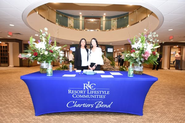Two staff members at a reception desk with flowers