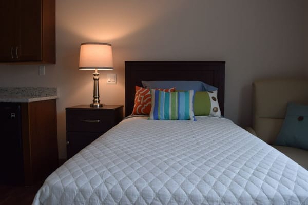 Well-decorated private resident room with a bed and lamp