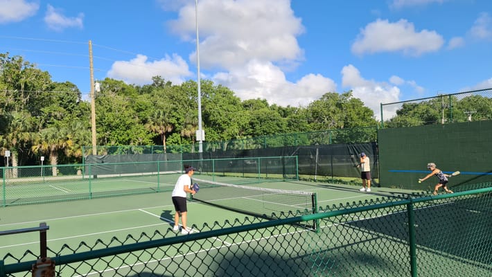 Two residents playing tennis on the court at Crown Assisted Living