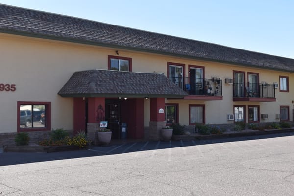 Main entrance of Rose Court Senior Living facility with flowers and parking area.