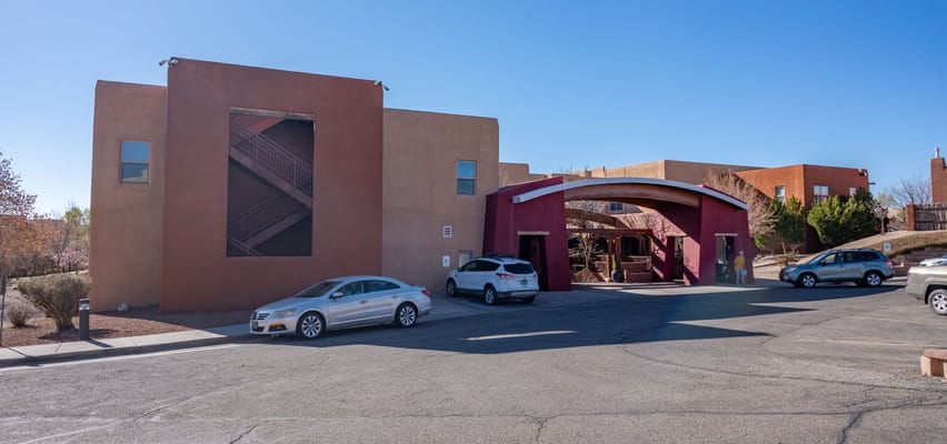 Entrance of The Montecito Santa Fé senior living facility with parked cars.