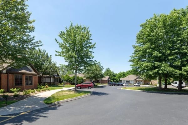 Clear sunny day view of the entrance to Deane Hill Place with landscaped trees.