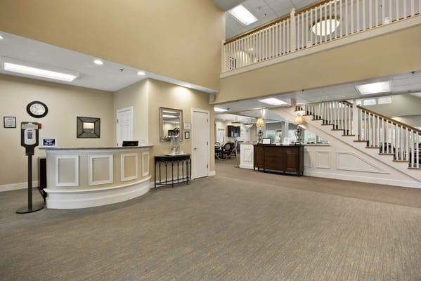 A bright common area with a reception desk and staircase