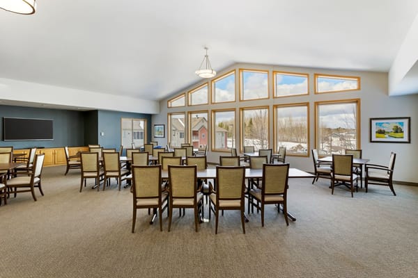 Spacious common area with tables and chairs and large windows
