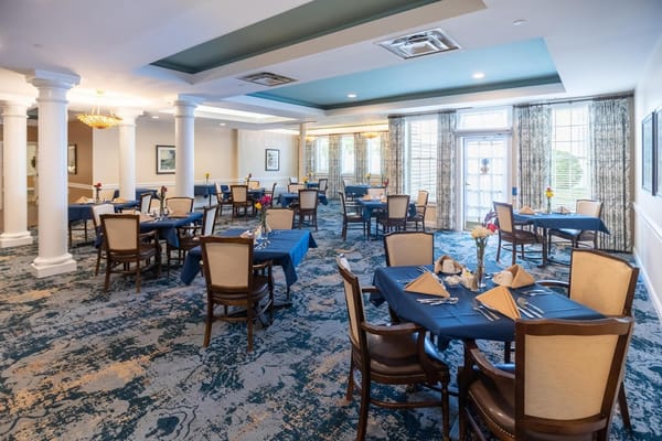 Seating arrangement in the dining room at East Village Place with blue tablecloths and floral centerpieces