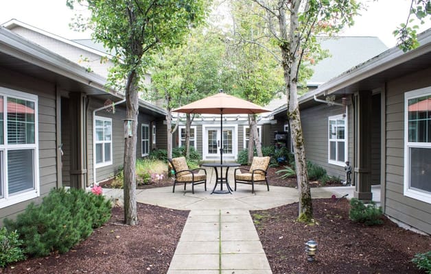 A serene courtyard with seating under an umbrella at Evergreen Memory Care