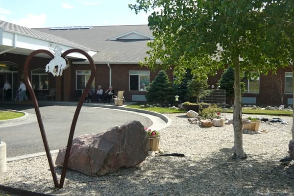 Exterior view of assisted living facility with landscaping and residents