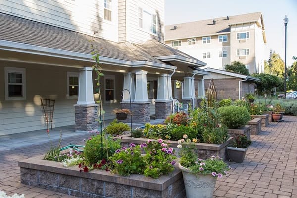 Lush garden with flowers and greenery outside Garden Way Retirement Community.