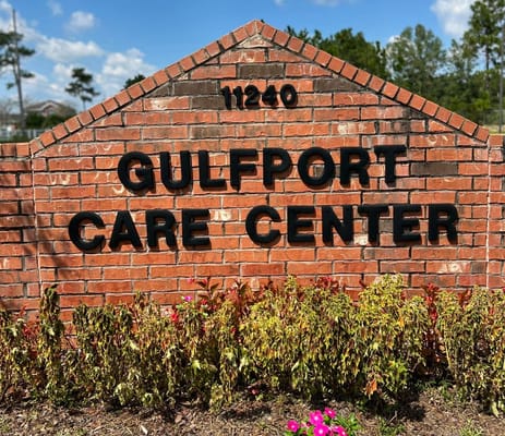 Brick sign for Gulfport Care Center with landscaped flowers