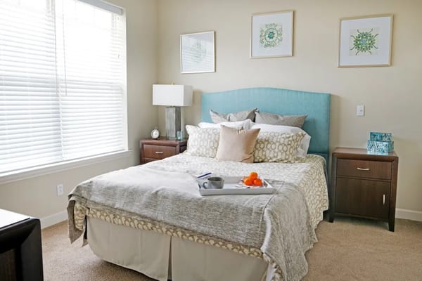 Well-decorated private resident room with a bed and nightstand