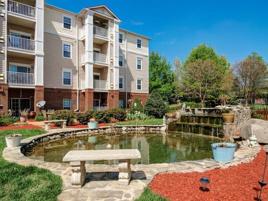 Outdoor garden area with a pond and apartment building