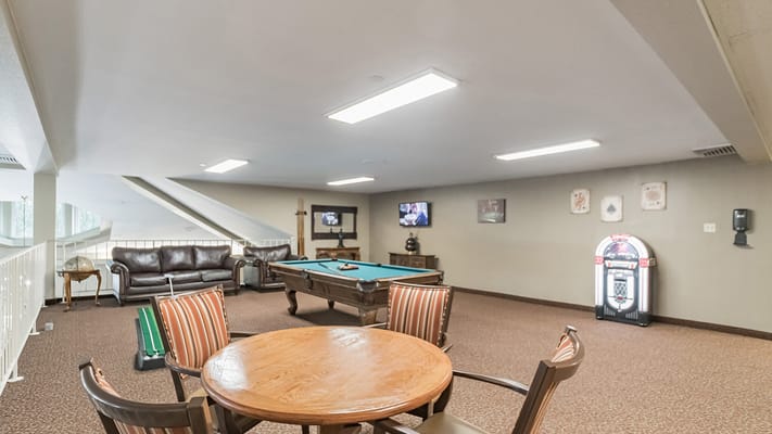A lounge area featuring a pool table, seating, and entertainment options.