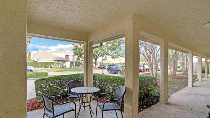 Patio area with a table and chairs surrounded by greenery