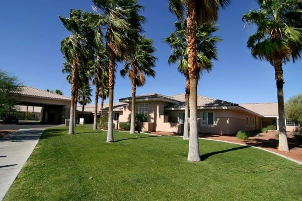Exterior view of a senior living facility surrounded by palm trees