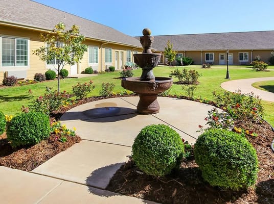 A decorative fountain surrounded by lush gardens at Legend at Council Road.