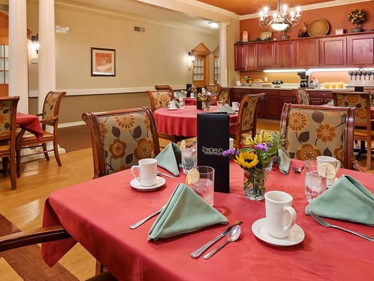 Colorful dining room setup with tables and flowers.