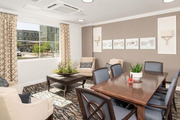 A bright and inviting common room with a dining table and seating area.
