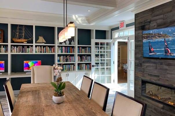 A modern library and study area with wooden table, bookshelves, and computers.