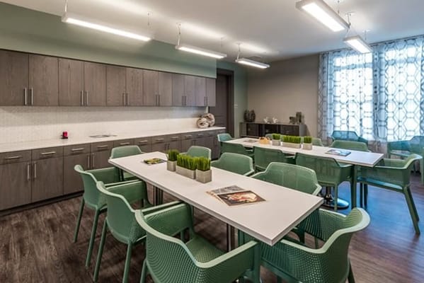 Spacious common area with tables and green chairs
