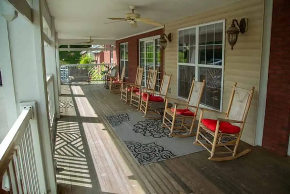Wooden rocking chairs on a porch with decorative rug