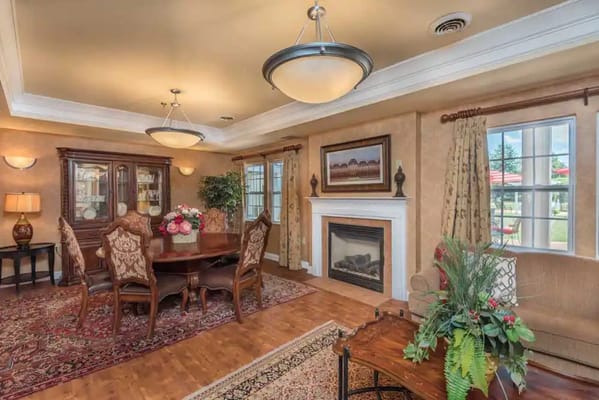 Cozy dining room featuring a wooden table, elegant chairs, and a fireplace.