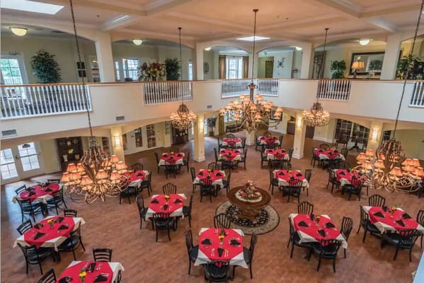 Spacious dining area with red table settings and chandeliers