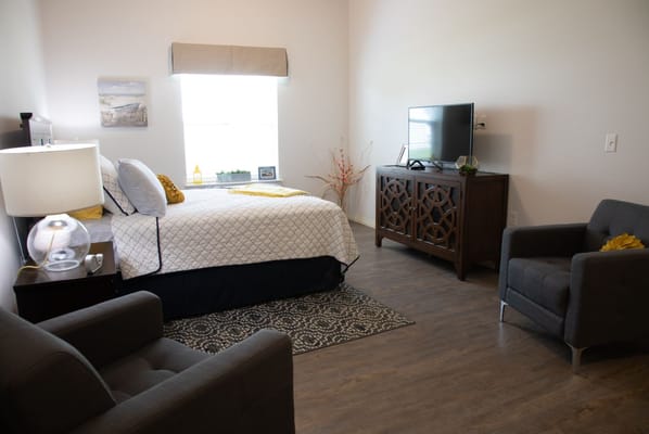 Bright and welcoming bedroom with a bed, television, and seating area.