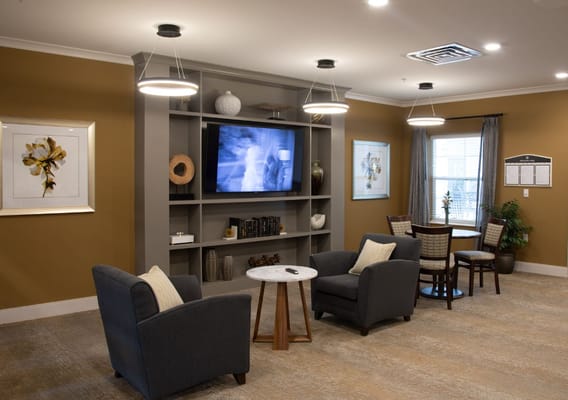 Cozy common area with chairs, a table, and a television.