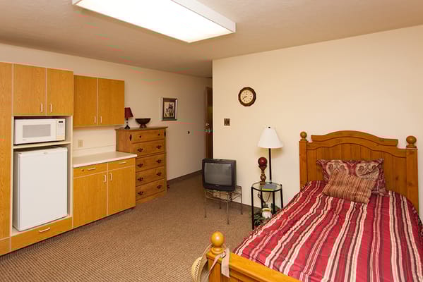 Cozy interior of a resident room with a bed and kitchenette