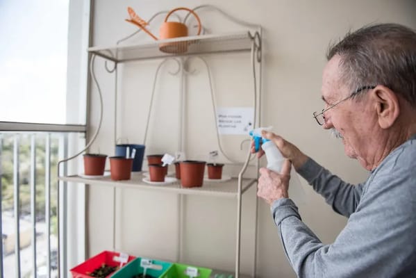 Resident tending to plants on a balcony
