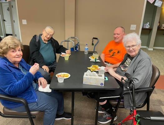 Four senior residents enjoying snacks at a table
