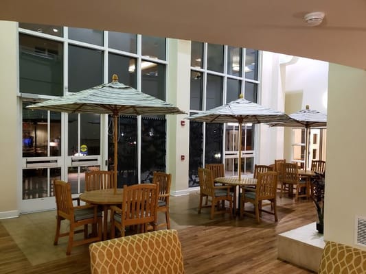 Common area with tables and umbrellas in a bright lobby