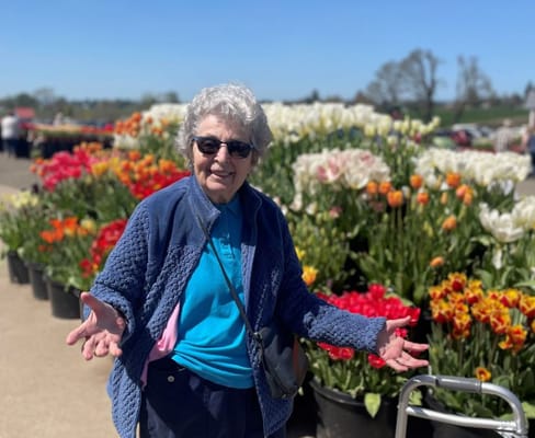 Elderly woman enjoying flowers in a garden