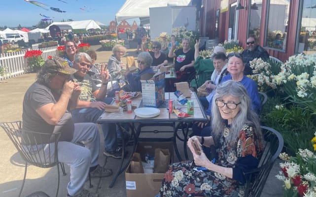 Residents enjoying a meal outdoors with activities in the background