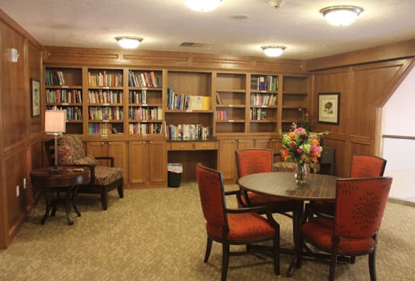 A welcoming library space with bookshelves, a reading chair, and a floral centerpiece on a table.