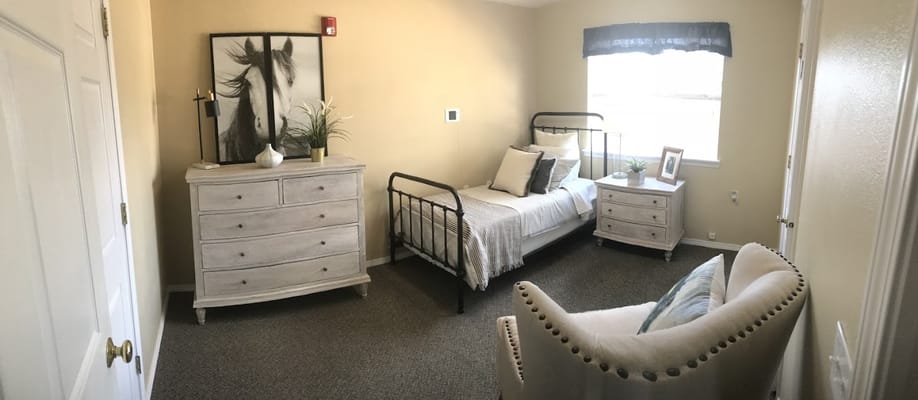 A well-furnished bedroom with a bed, dresser, and seating area.